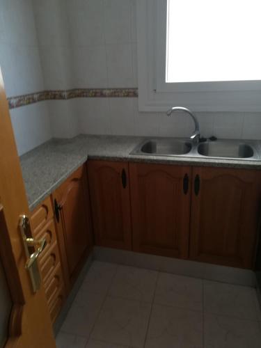 a kitchen with wooden cabinets and a sink and a window at Ca l'Estrella II L'Estartit in L'Estartit