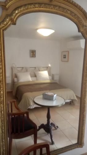 a mirror reflecting a bedroom with a bed and a table at La Radassière in Cotignac