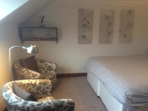 um quarto com uma cama, uma cadeira e um candeeiro em Arden Croft em Pershore
