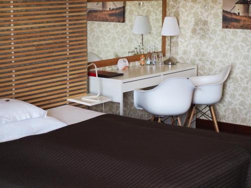 a bedroom with a bed and a desk with two white chairs at Hotel Spichlerz Lubawa in Lubawa