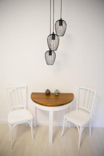 a dining room table with two chairs and a table and two lights at Morzsi Apartman in Szilvásvárad
