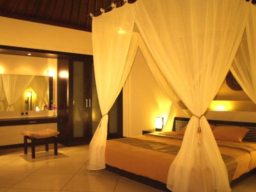 a bedroom with a bed with white curtains at Nike Villas in Sanur