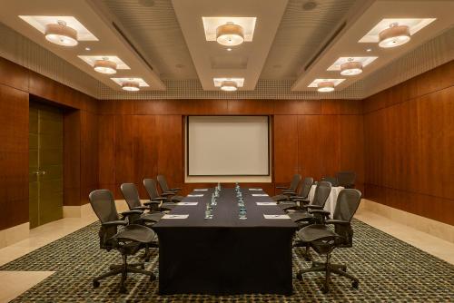 a conference room with a table and chairs and a whiteboard at Safir Fintas Hotel Kuwait in Kuwait