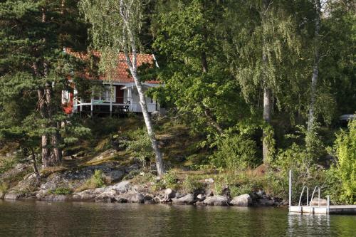 ein Haus am Ufer eines Flusses mit Bäumen in der Unterkunft Sjöstuga vid Bunn Gränna - Uddastugan in Gränna