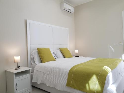 a white bedroom with a large bed with yellow pillows at B&B Via Cavour 32 in Siracusa