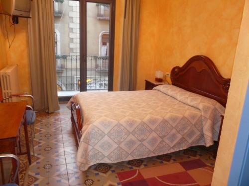 1 dormitorio con cama y ventana grande en Hostal Adarnius, en La Bisbal