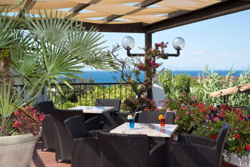 a patio with tables and chairs and flowers at Hotel Casa Di Meglio in Ischia