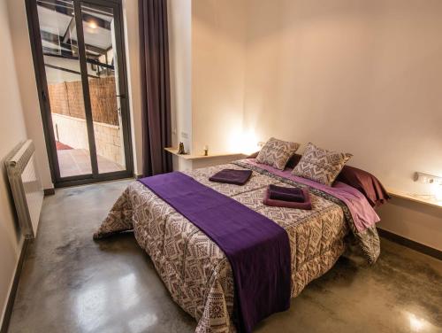 a bedroom with a large bed with a purple blanket at Cal Dansa in Berga