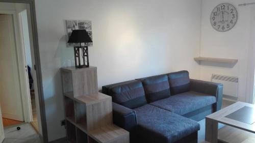 - un salon avec un canapé bleu et une horloge murale dans l'établissement Mèze, 400 mètres de la Plage, à Mèze