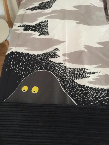 a bed with a black and white comforter with yellow eyes at Hotelli Kaivo in Naantali
