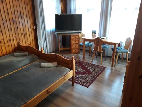 a living room with a bed and a tv and a table at Schody Do Nieba in Zakopane