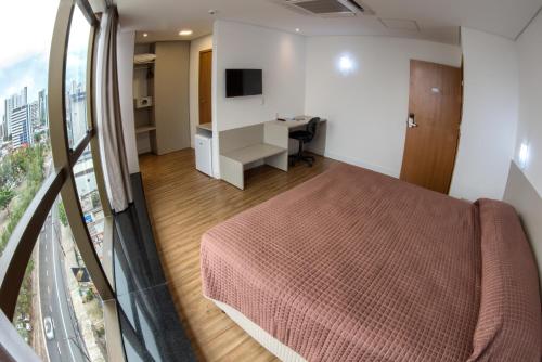 a bedroom with a bed and a desk and a window at Marante Executive Hotel in Recife