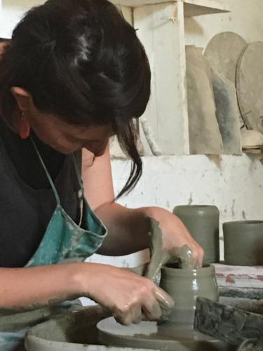 a woman making a pot on a pottery wheel at La Fratta Art - House in Marsciano