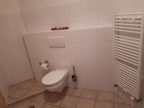 um WC branco numa casa de banho com uma escova de WC em Ferienwohnung Gashi em Winterberg