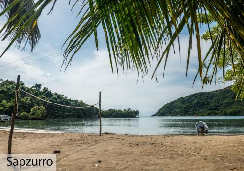 a hammock on a beach next to a body of water at Tacarcuna Lodge in Capurganá