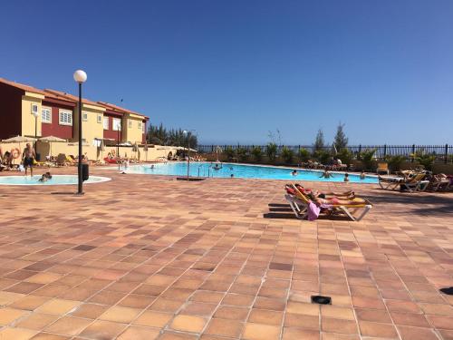 un grupo de personas sentadas en sillas cerca de una piscina en Vivienda Las Velas, en Maspalomas