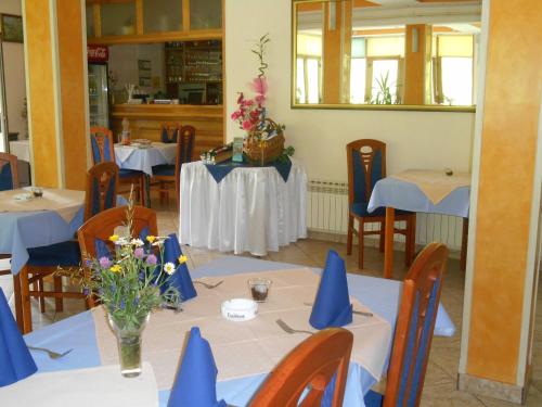 a restaurant with tables with blue napkins and flowers on them at Motel Bavaria in Foča