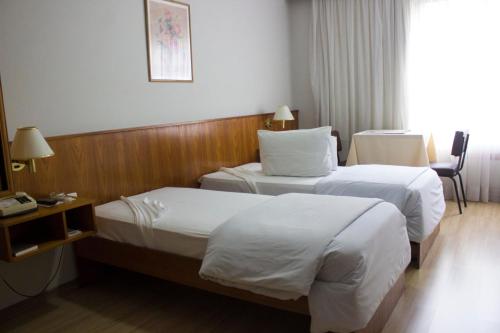 a hotel room with two beds and a desk at Hotel Portal in Santana do Livramento