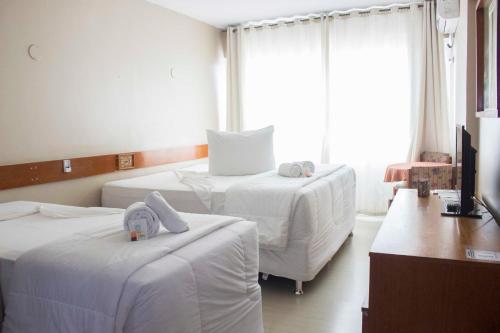 um quarto de hotel com duas camas e uma televisão em Hotel Portal em Santana do Livramento