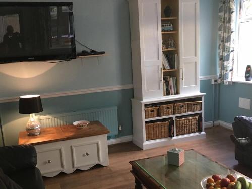 a living room with a table and a tv on the wall at Bedrock Lodge in Bristol
