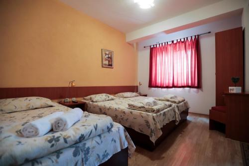 1 dormitorio con 2 camas y una ventana roja en Bakal Apartments, en Ohrid