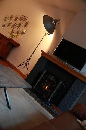 a living room with a fireplace with a television and a lamp at Temps de Pose in Ypres