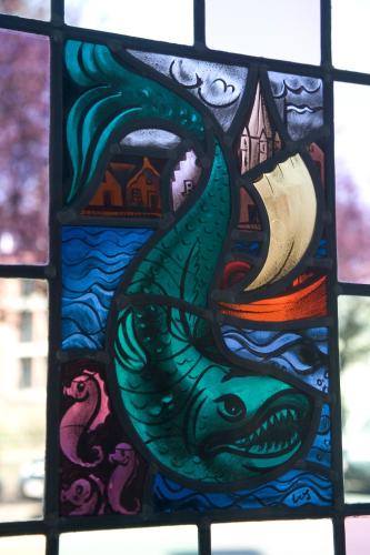 a stained glass window with a fish and a book at Domus Portus in Dendermonde
