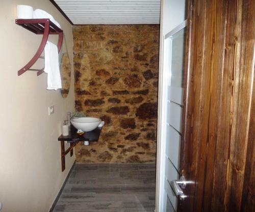 a bathroom with a sink and a stone wall at Albergue-Hostel Casa da Gandara in Boimorto