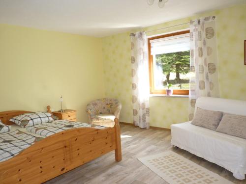 ein Schlafzimmer mit einem Bett, einem Fenster und einem Stuhl in der Unterkunft Haus Am Friedrichsbach in Pöhla