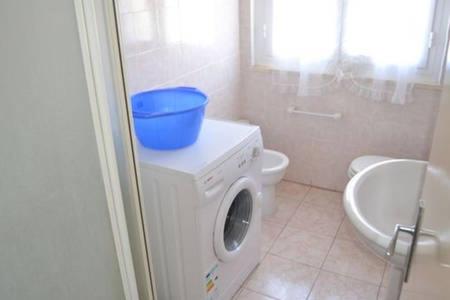un baño con un cubo encima de una lavadora en Appartamento a Cecina mare, en Marina di Cecina