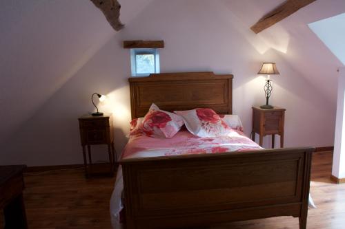 Schlafzimmer mit einem Holzbett mit rosa Bettwäsche und Kissen in der Unterkunft Au Coeur des Châteaux in Chambon-sur-Cisse