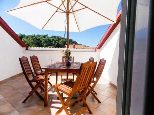 een eetkamer met een tafel en stoelen en een parasol bij Apartments Ribarić in Rab