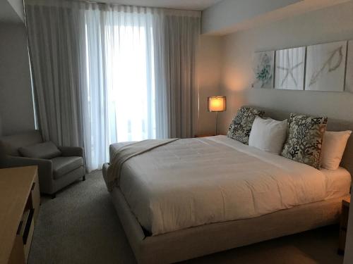 a bedroom with a bed and a chair and a window at Beach Walk Resort De Lux Apartment in Hallandale Beach