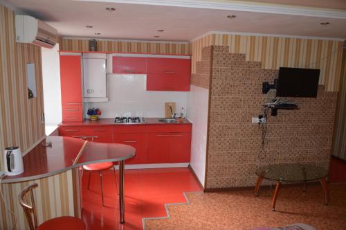 ヘルソンにあるCentral Supermarket apartment 1 roomのキッチン(赤いキャビネット、テーブル、椅子付)