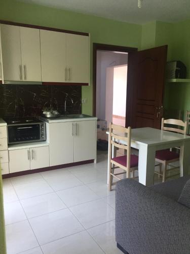 a kitchen with white cabinets and a table and chairs at Mana Apartments in Ksamil