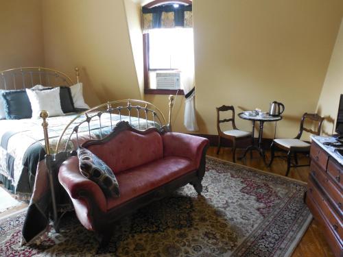 a bedroom with a bed and a red couch at Proctor Mansion Inn in Wrentham