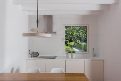 a white kitchen with a table and a window at Quinta de Santa Clara in Ponta Delgada