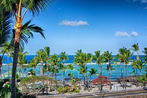 uma vista para uma praia com palmeiras e para o oceano em Beach Villas Kahaluu on Kona Coast em Kailua-Kona