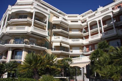 a tall white building with palm trees in front of it at Sharon Apartment in Victoria Beach in Menton