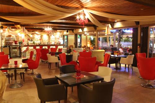 un restaurante con mesas y sillas rojas y un bar en Dimitra Hotel, en Faliraki