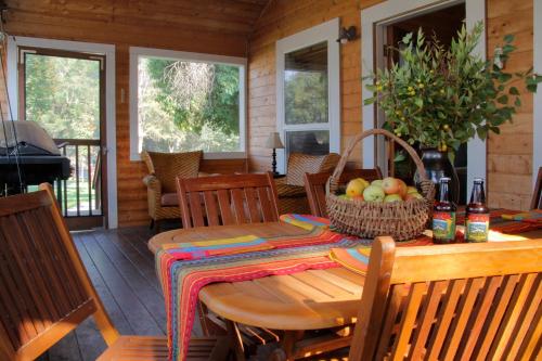 uma mesa de madeira e cadeiras num alpendre com uma sala de jantar em Coho Cottages em Willow Creek