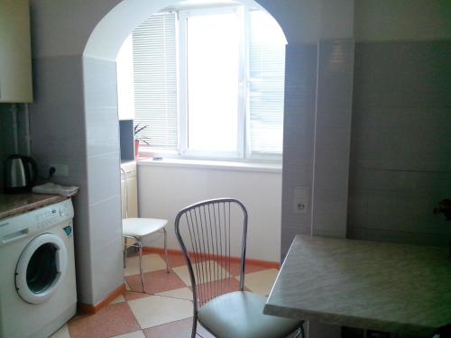 a kitchen with a table and a chair and a washing machine at Homelike flat near the IEC on Levoberezhnaya in Kyiv