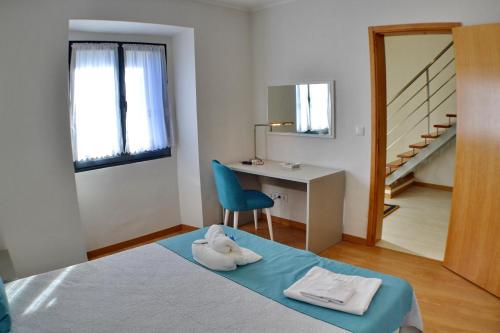 1 dormitorio con 1 cama con silla azul y escritorio en Casa da Água Quente 2, en Furnas