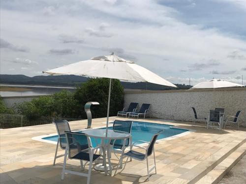 a table and chairs with an umbrella next to a pool at Casa de Campo às margens do lago de furnas in Boa Esperança