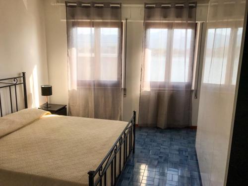 een slaapkamer met een groot bed en 2 ramen bij Romantica Bocca di Magra in Bocca di Magra