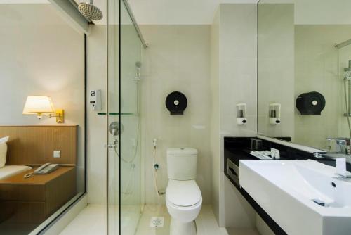 La salle de bains est pourvue de toilettes, d'un lavabo et d'une douche. dans l'établissement New Cape Inn, à Singapour