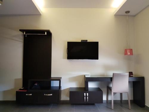 a room with a desk and a television on a wall at Remfort Hotel in Santa Ana