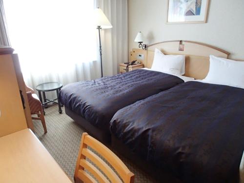 a hotel room with two beds and a table at Hotel Resol Sapporo Nakajima Koen in Sapporo