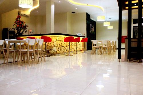 a restaurant with white tables and red chairs at Green Garden Hotel in Tuban