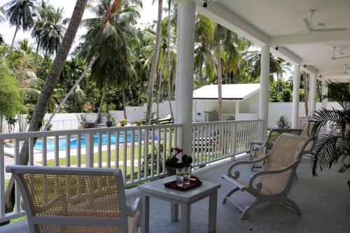 a porch with chairs and a table and a pool at Plantation House in Hikkaduwa